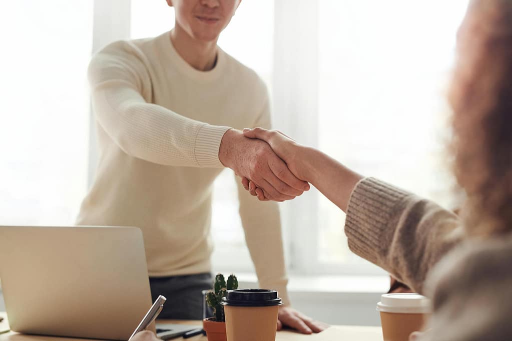 Business professionals shaking hands over coffee in a modern office.